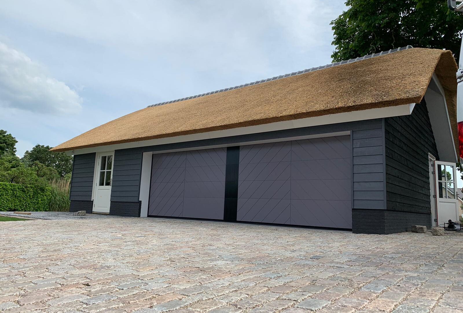 Dubbele garagedeur in schuur met rieten kap
